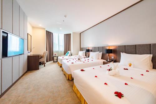 una camera d'albergo con due letti con rose sopra di Mường Thanh Holiday Suối Mơ Hạ Long a Ha Long