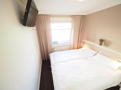 - une chambre avec un lit blanc et une télévision dans l'établissement Appartement-173, à Westerland
