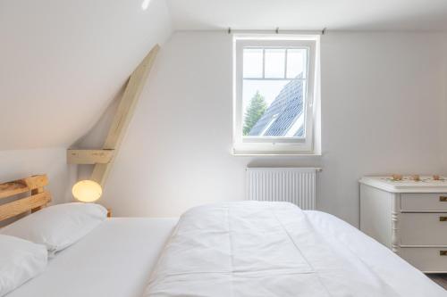ein weißes Schlafzimmer mit einem Bett und einem Fenster in der Unterkunft Bootshaus in Husum