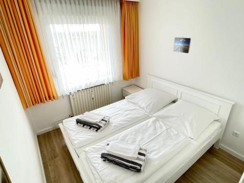 ein weißes Bett mit zwei Handtüchern auf einem Zimmer in der Unterkunft Appartement 162 in Westerland