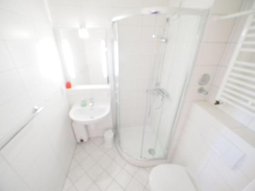 ein weißes Bad mit einer Dusche und einem Waschbecken in der Unterkunft Appartement 162 in Westerland