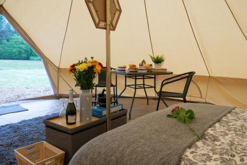 a tent with a table and a table with flowers at Forest Edge Glamping in Gittisham