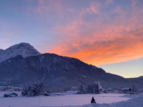 a sunset with a mountain in the background with snow at Guesthouse Rosengarten in Dobbiaco