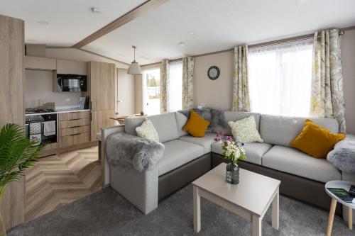 a living room with a grey couch and yellow pillows at The Beach Hut, Burghead in Burghead