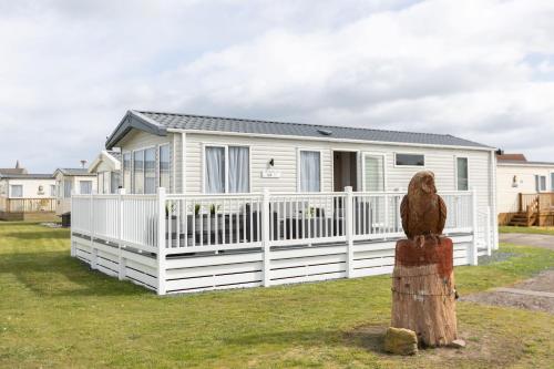 a house with a white fence and an eagle statue at The Beach Hut, Burghead in Burghead