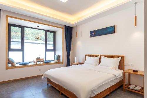 a bedroom with a large white bed and a window at ManBuYunDuan.Theme Inn in Wutai