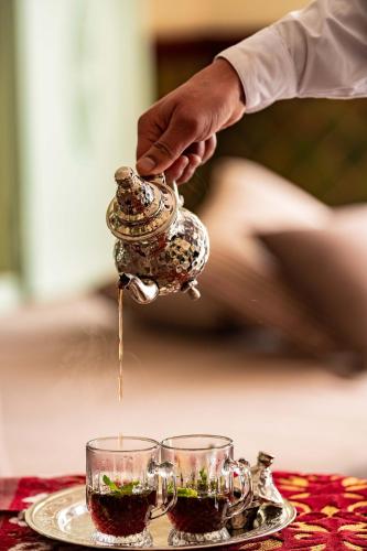 a person pouring tea from a tea pot into two glasses at TMK Flora Park by Turismark - Adults Only in Hammamet