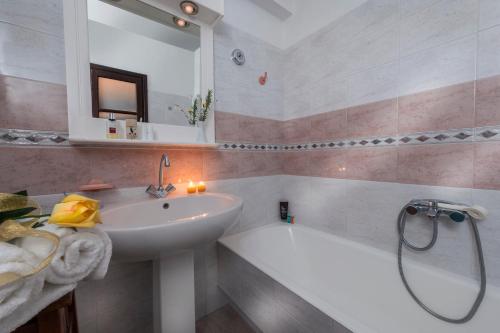 e bagno con lavandino, specchio e vasca. di Niriides Apartments a Kipri