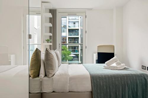 a bedroom with a bed with white sheets and a window at Three Bedroom Serviced apartment in Old Street in London