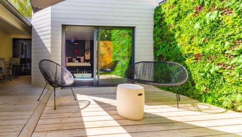 twee stoelen op een patio naast een muur bij Le Secret - Nuit romantique avec Jacuzzi privatif - Champagne offert - Climatisation in Nantes