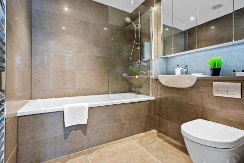 a bathroom with a tub and a toilet and a sink at Three Bedroom Serviced apartment in Old Street in London