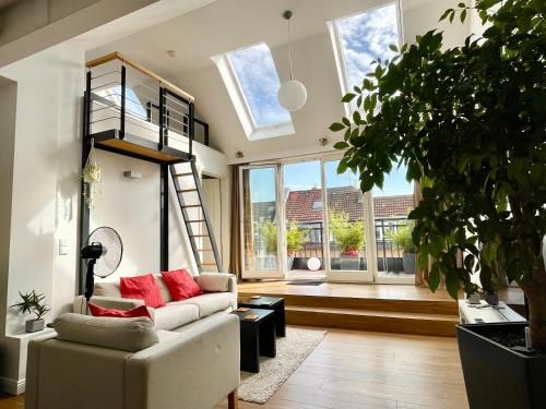 een woonkamer met een bank, een ladder en ramen bij Apartment in Pempelfort - Central in Düsseldorf