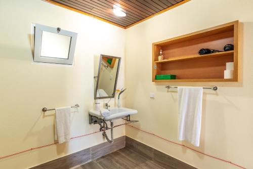 y baño con lavabo y espejo. en 2 bedrooms appartement with shared pool furnished terrace and wifi at Prazeres 5 km away from the beach, en Campanário