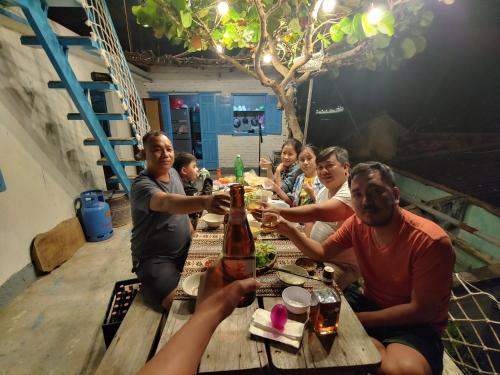 a group of people sitting around a wooden table at nhà Ba cơm Má in Phương Phi