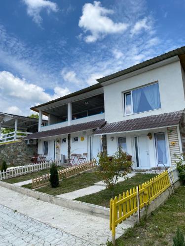 a white house with a yellow fence in front of it at Casutele verzi din Ocnele Mari in Ocnele Mari