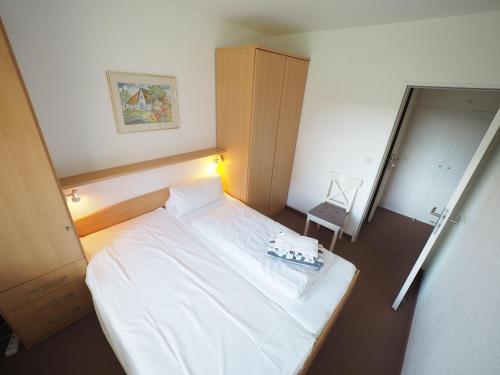 um pequeno quarto com uma cama branca e uma cadeira em Appartement-84 em Westerland