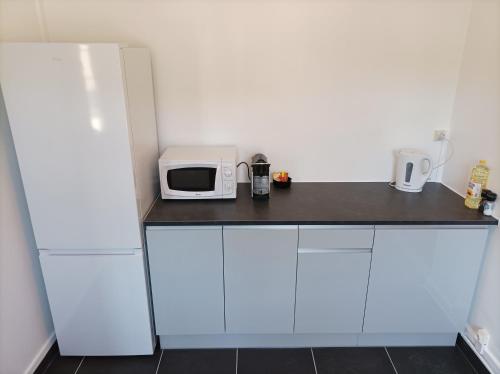 a kitchen with a white refrigerator and a microwave at O'Couvent - Appartement 331 - 2 chambres - 80 m2 - Troisième étage in Salins-les-Bains