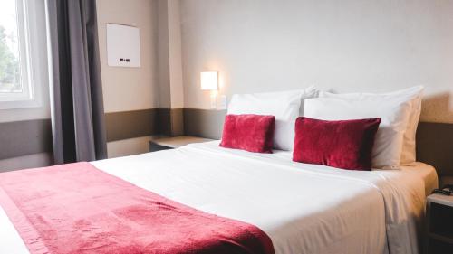 a bedroom with a large white bed with red pillows at Work Hotel São Leopoldo in São Leopoldo