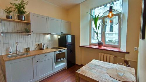 cocina con armarios blancos, mesa y ventana en Cozy studio and standard apartments in the heart of Oldtown, en Vilna