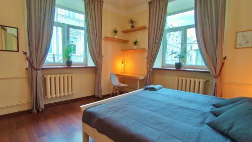 Un dormitorio con una cama azul y algunas ventanas en Cozy studio and standard apartments in the heart of Oldtown, en Vilna