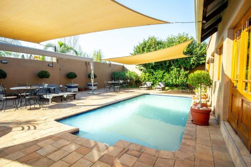 una piscina en un patio con sombrilla en Afrique Boutique Hotel O.R. Tambo en Boksburg
