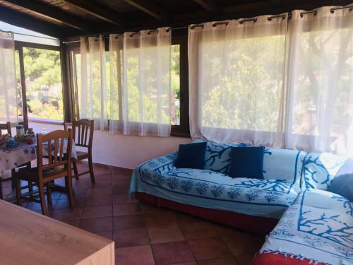 ein Wohnzimmer mit einem Sofa, einem Tisch und Fenstern in der Unterkunft Mondello Aiace 40 in Mondello