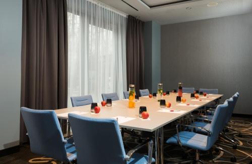 a conference room with a long table and blue chairs at Leonardo Hotel Offenbach Frankfurt in Offenbach