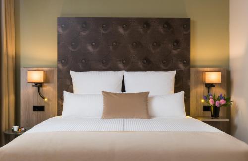 a bedroom with a large white bed with two lamps at Leonardo Hotel Offenbach Frankfurt in Offenbach