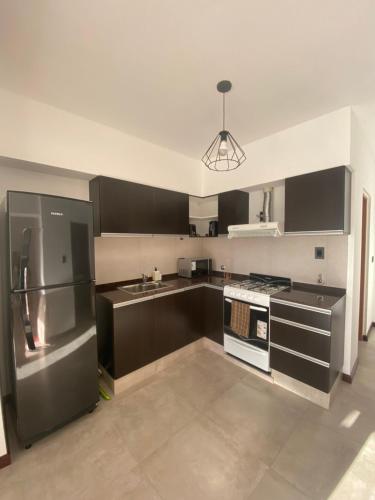 eine Küche mit schwarzen Schränken und einem Kühlschrank aus Edelstahl in der Unterkunft Hermoso departamento céntrico con estacionamiento in Paraná