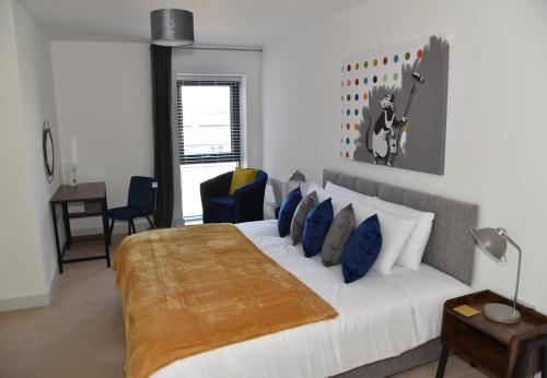 um quarto com uma grande cama branca com almofadas azuis em FANTASTIC 2 Dbl Bedroom Apt. FREE off-road parking em Swindon