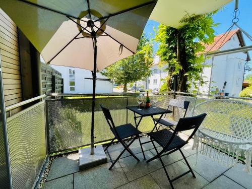 a table and chairs on a balcony with an umbrella at Ferien-Apartment Silberweide - mit priv Strandzugang in Friedrichshafen