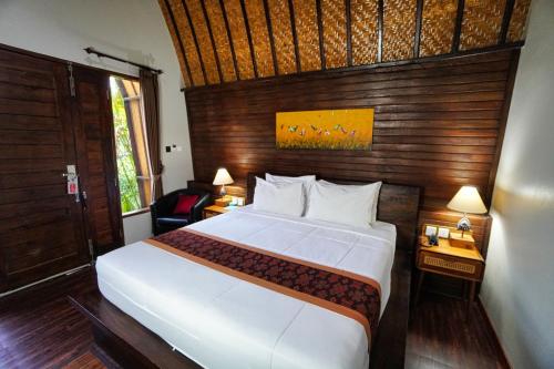 a bedroom with a large bed with a wooden wall at Adil Villa & Resort in Ubud