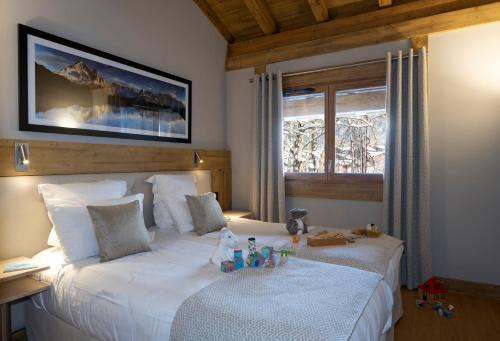 a bedroom with a large white bed with toys on it at MGM Hôtels & Résidences - Résidence Chalets Elena in Les Houches
