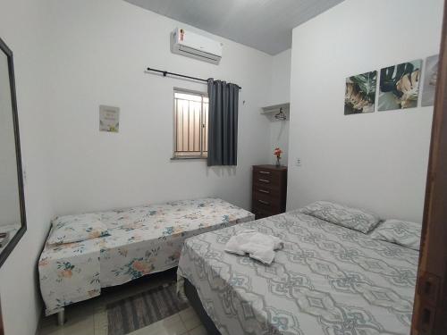 a bedroom with two beds and a window at Chalé Conforto de Casa in Barreirinhas