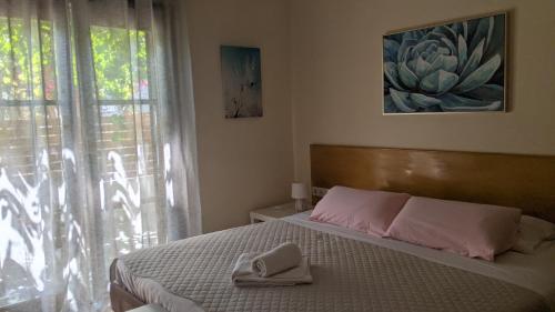 a bedroom with a bed with pink pillows and a window at Pension Irene in Sougia