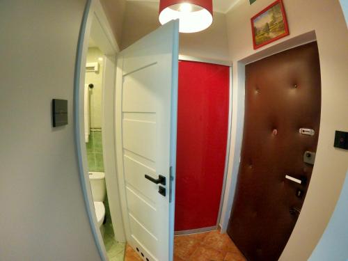 a bathroom with a red door and a mirror at Faryna Apartament in Ruciane-Nida