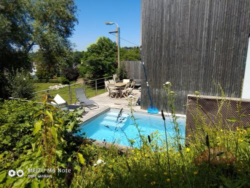 a swimming pool with a table and chairs in a yard at Maison à la porte des Ardennes in Verviers