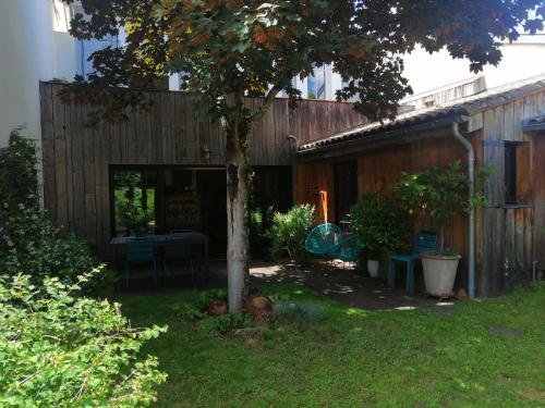 une cour avec un arbre, une table et des chaises dans l'établissement Maison de charme, à Bordeaux