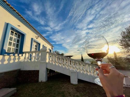 a person holding a glass of wine in front of a house at Pousada Olival Vila do Segredo in Caçapava do Sul