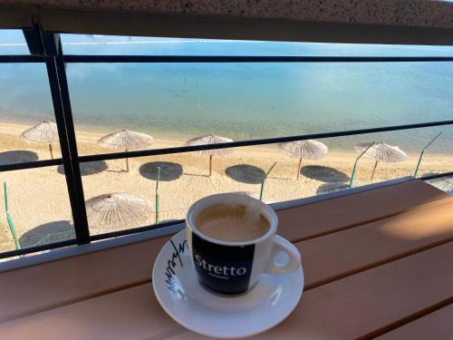 a cup of coffee on a window sill with a view of the beach at Apartments Lolo in Privlaka