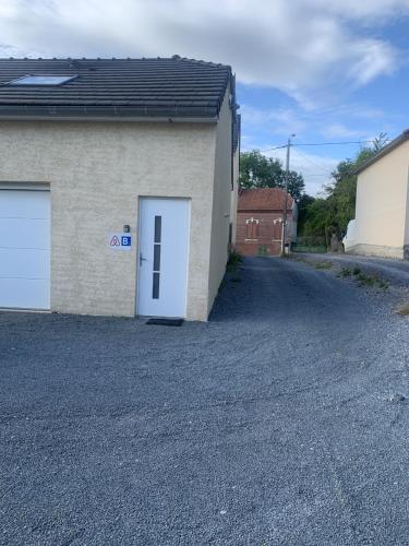 a garage with a white door in a driveway at Le Gîte du Val de Noye in Ailly-sur-Noye