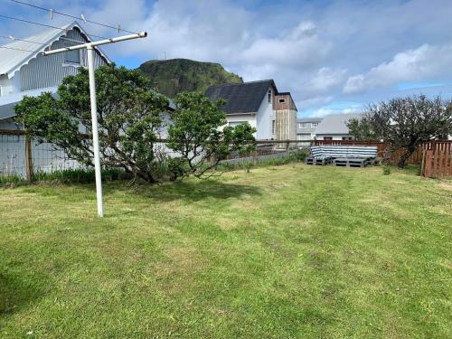 un patio con un poste en la hierba en Lítið einbýlishús á besta stað., en Vestmannaeyjar