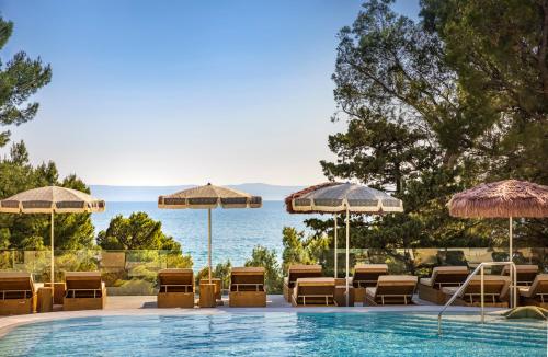einen Pool mit Stühlen und Sonnenschirmen in der Unterkunft DALMACIJA PLACES HOTEL by Valamar in Makarska
