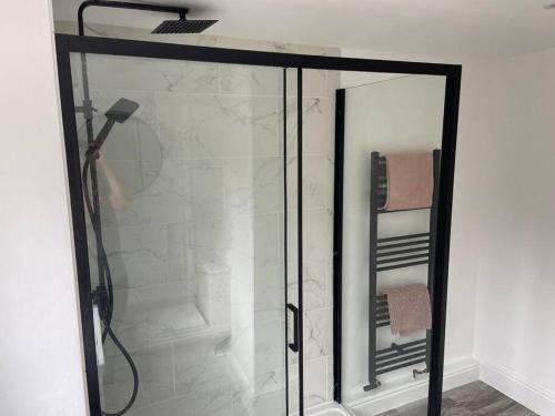 a shower with a glass door in a bathroom at Modern Ground Floor Garden Apartment With Parking in South Hayling