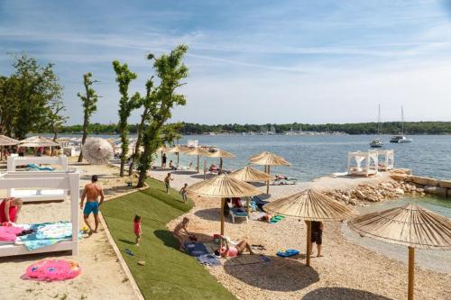 a group of people on a beach with umbrellas at VILLA SILVIA - FUNTANA in Funtana