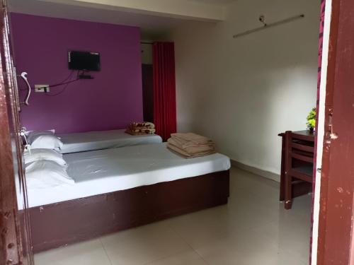 a small room with a bed with a purple wall at Voyage Munnar Laya Home Stay in Suryanelli