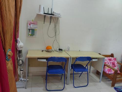 a desk with two blue chairs in a room at Homestay Intan Payung Bukit Katil Tuah Perdana in Melaka