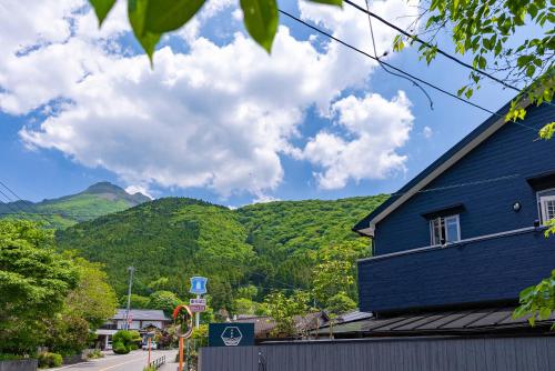 a blue building with mountains in the background at ETAVIA Yufuin Kinrinko in Yufuin