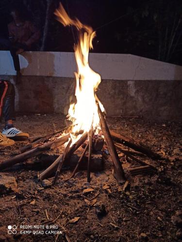 a fire is burning in front of a campfire at Voyage Munnar Laya Home Stay in Suryanelli
