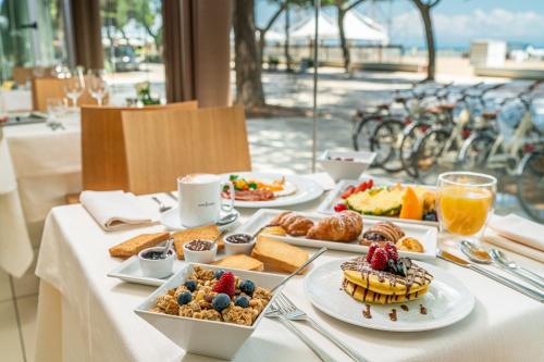 a table with plates of breakfast food on it at Hotel Europa Lignano in Lignano Sabbiadoro